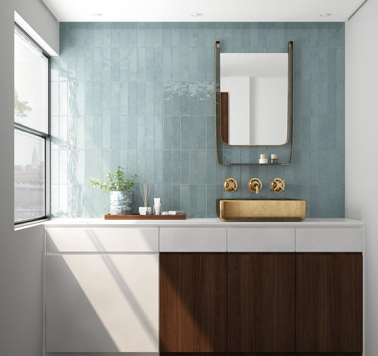Modern bathroom with wooden vanity, gold faucet, and green tiled wall.