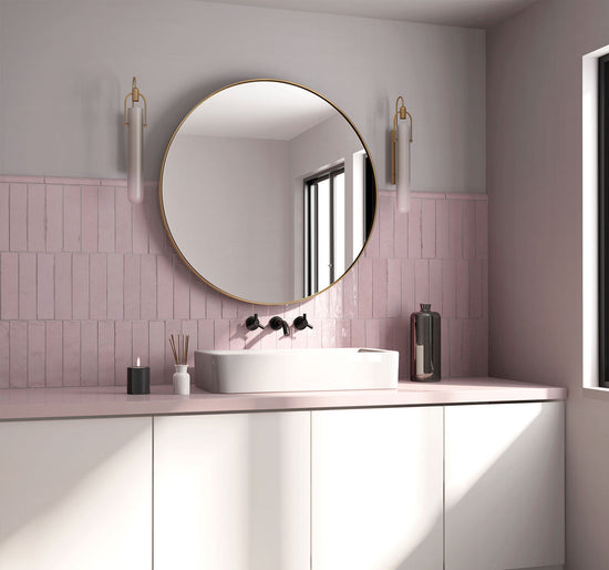 Modern bathroom with round mirror, pink tiles, and white vanity.